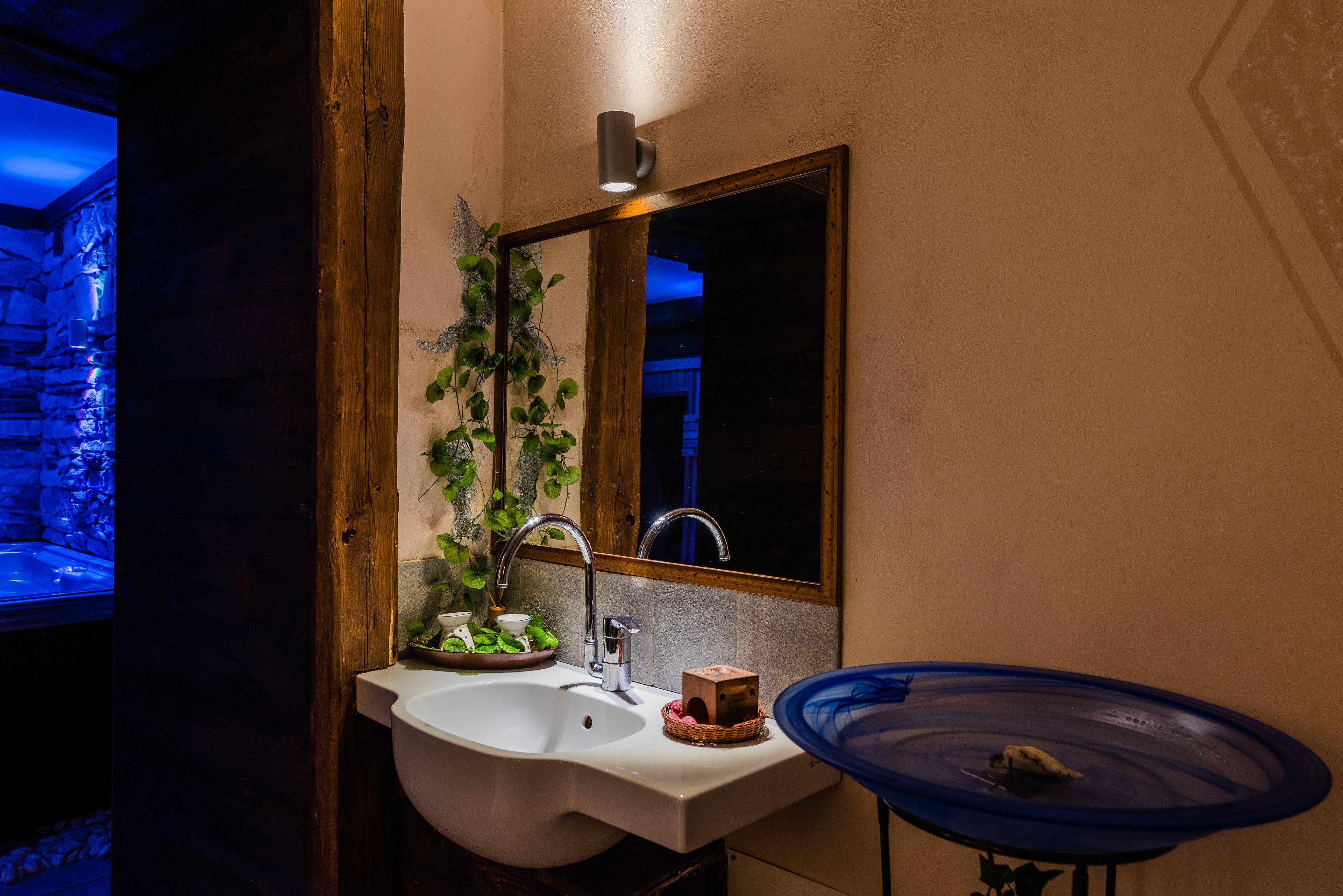 A bathroom with a sink, mirror, and a blue decorative bowl.