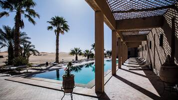 Relax by the pool surrounded by a serene desert landscape and shaded seating area.