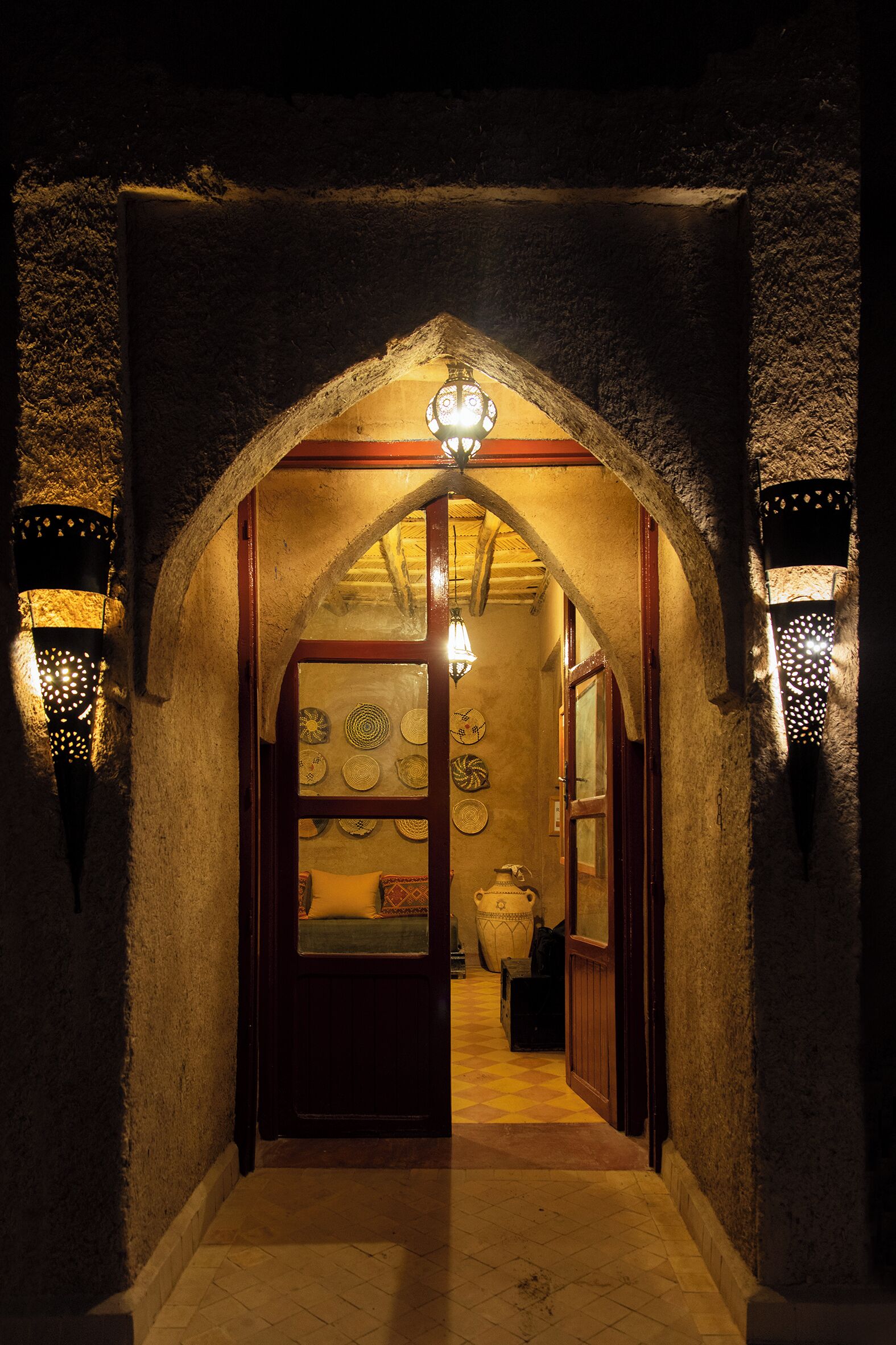 A narrow hallway with an arched ceiling, stone walls, and a wooden door.