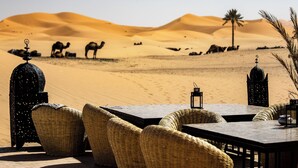 A desert landscape with sand dunes and camels in the background. - Hotel Kanz Erremal (Taouz)