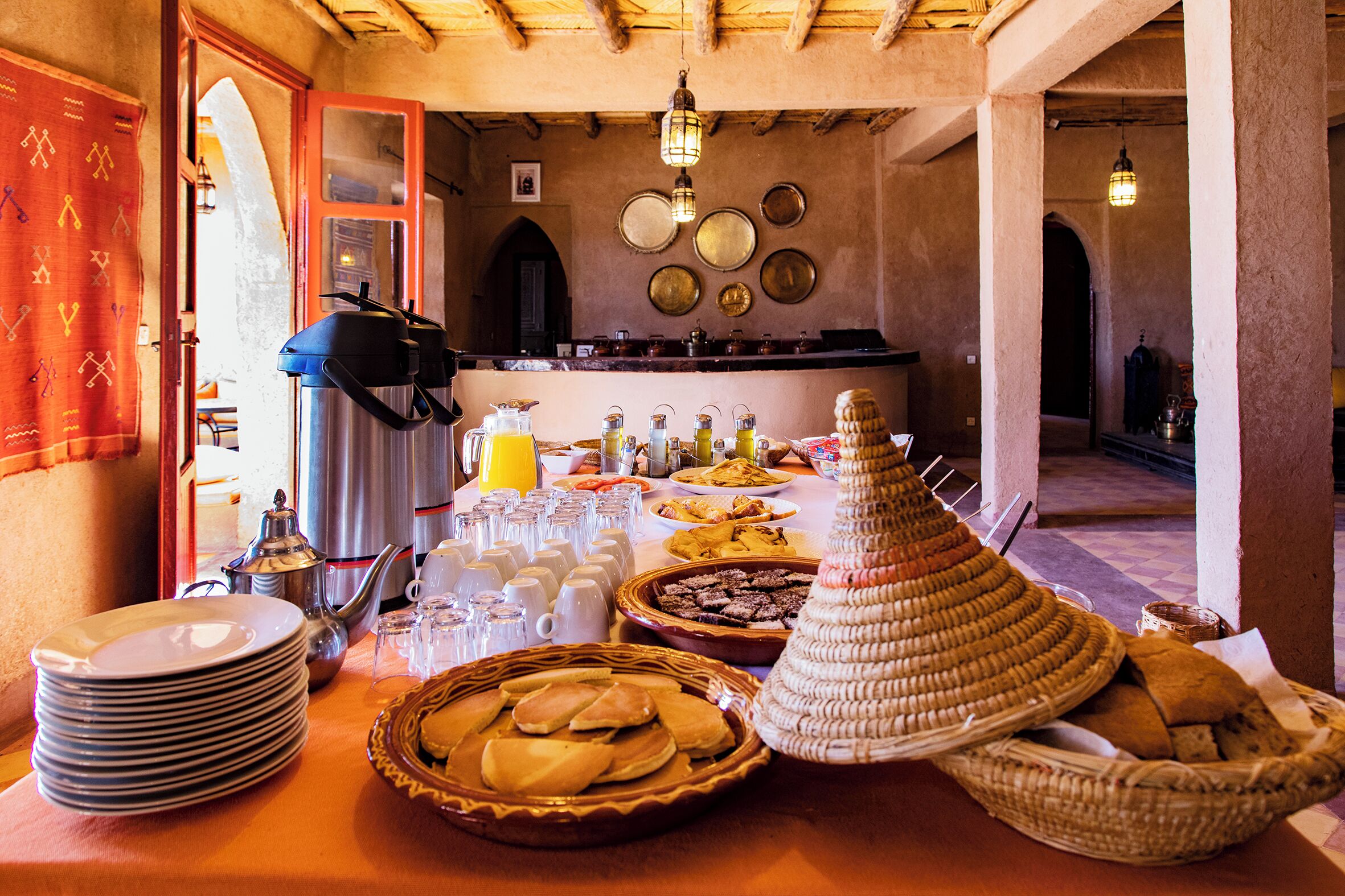Une table de buffet avec divers plats, assiettes et verres.