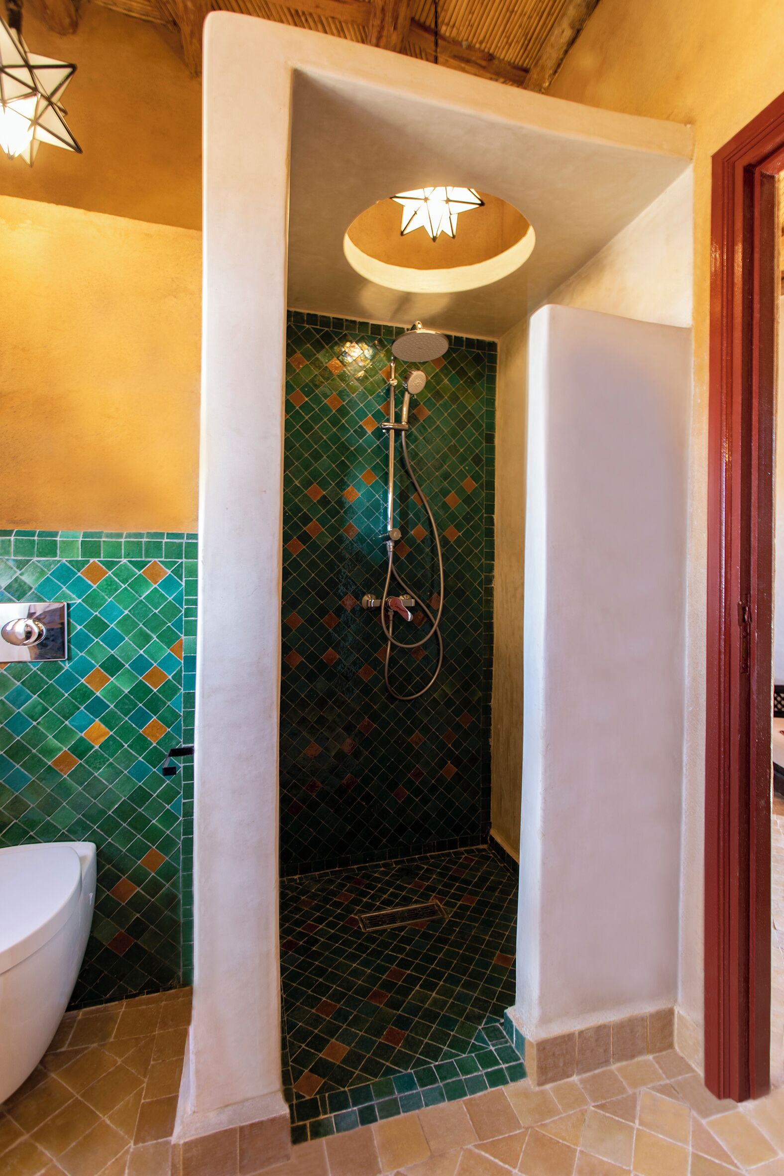 Un baño con ducha, paredes de azulejos y un inodoro.