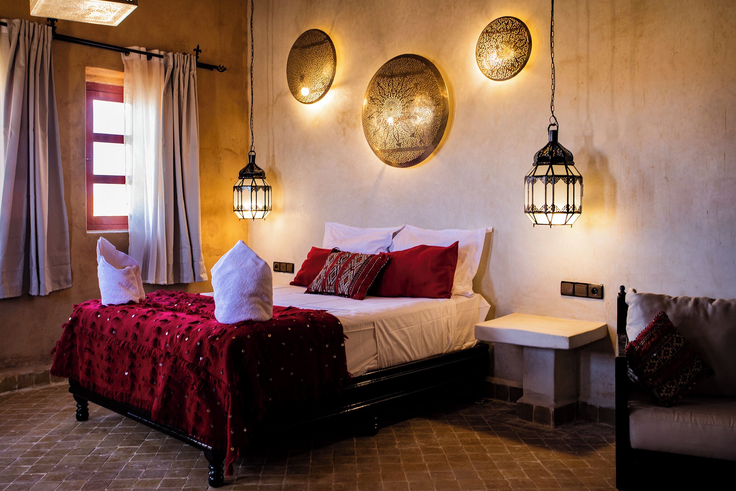 A bedroom with a bed, bedside tables, and decorative wall sconces.