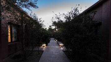 A pathway flanked by buildings and trees, leading to a distant structure.