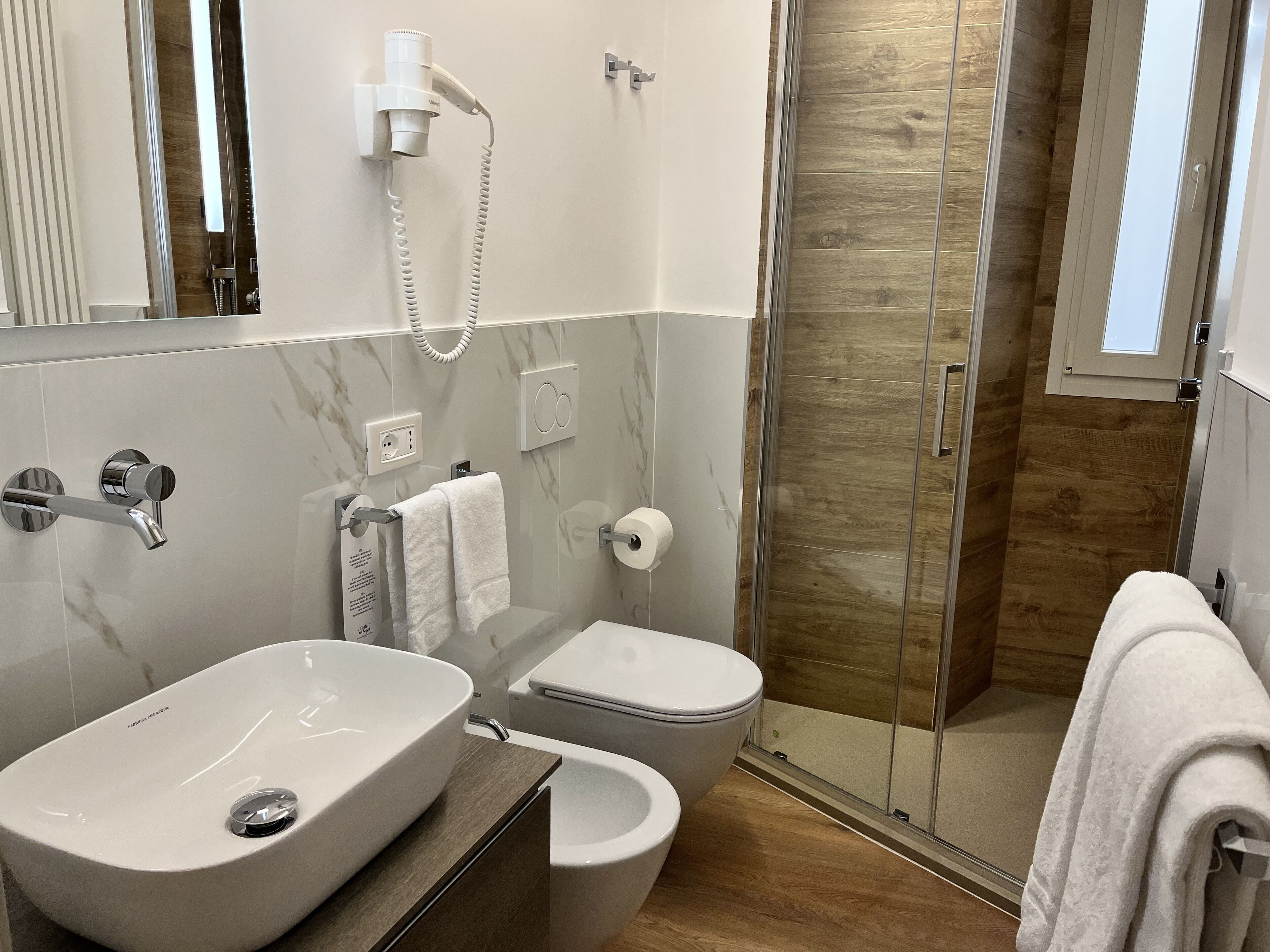 A modern bathroom with a large sink, toilet, and a glass shower enclosure.