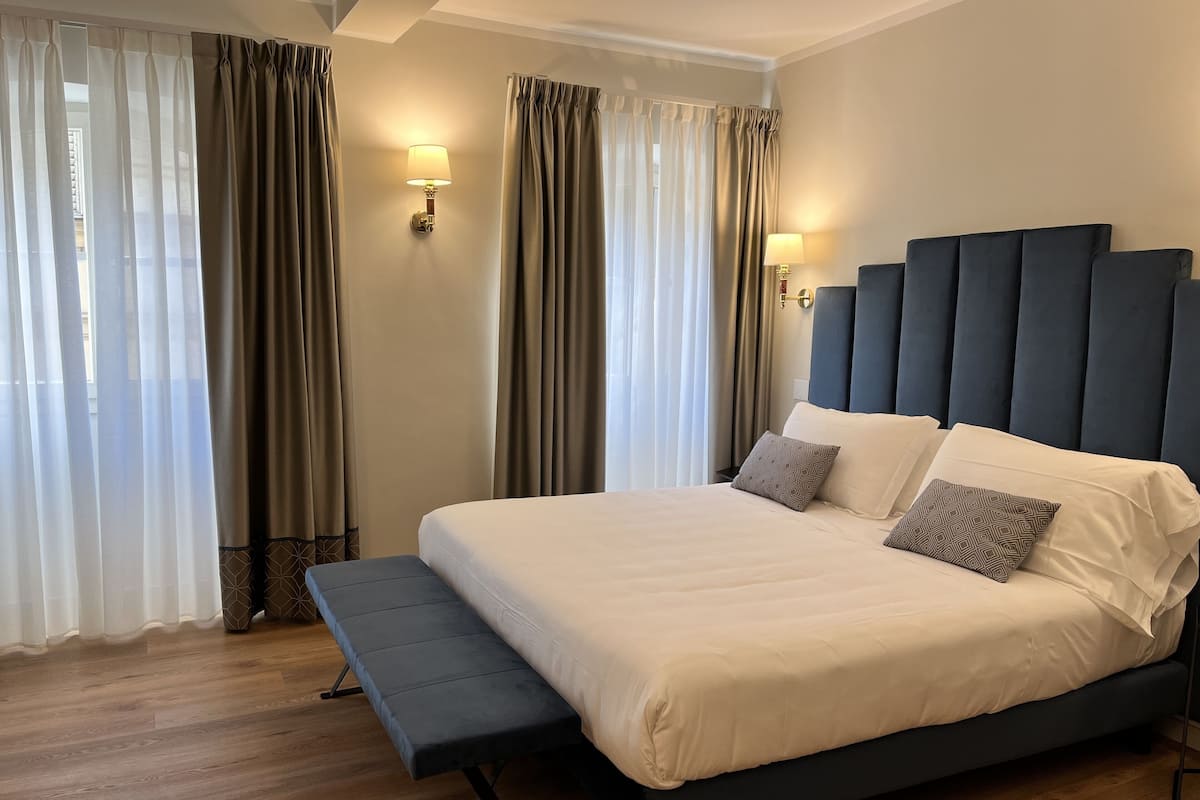 Een moderne hotelkamer met een groot bed, een bankje en twee wandlampen.