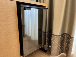 A modern room with a wooden cabinet, a black appliance, and patterned curtains.