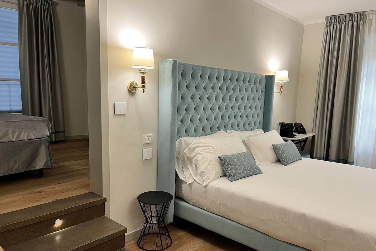 Een hotelkamer met een groot bed, een kleine tafel, een stoel, een bureau met een telefoon en een trap.