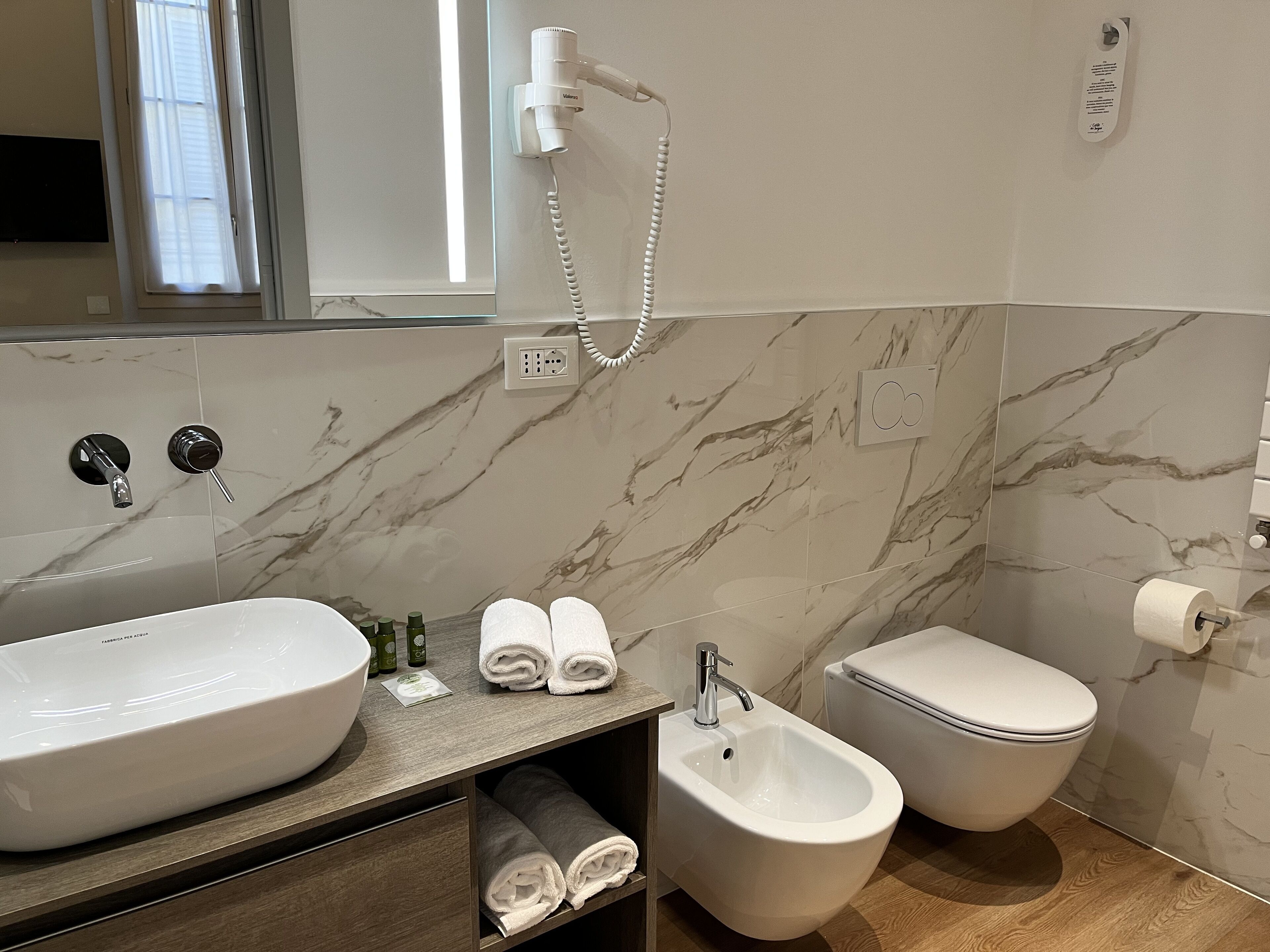 Un baño con un lavamanos grande blanco, un bidé, un inodoro y un espejo.