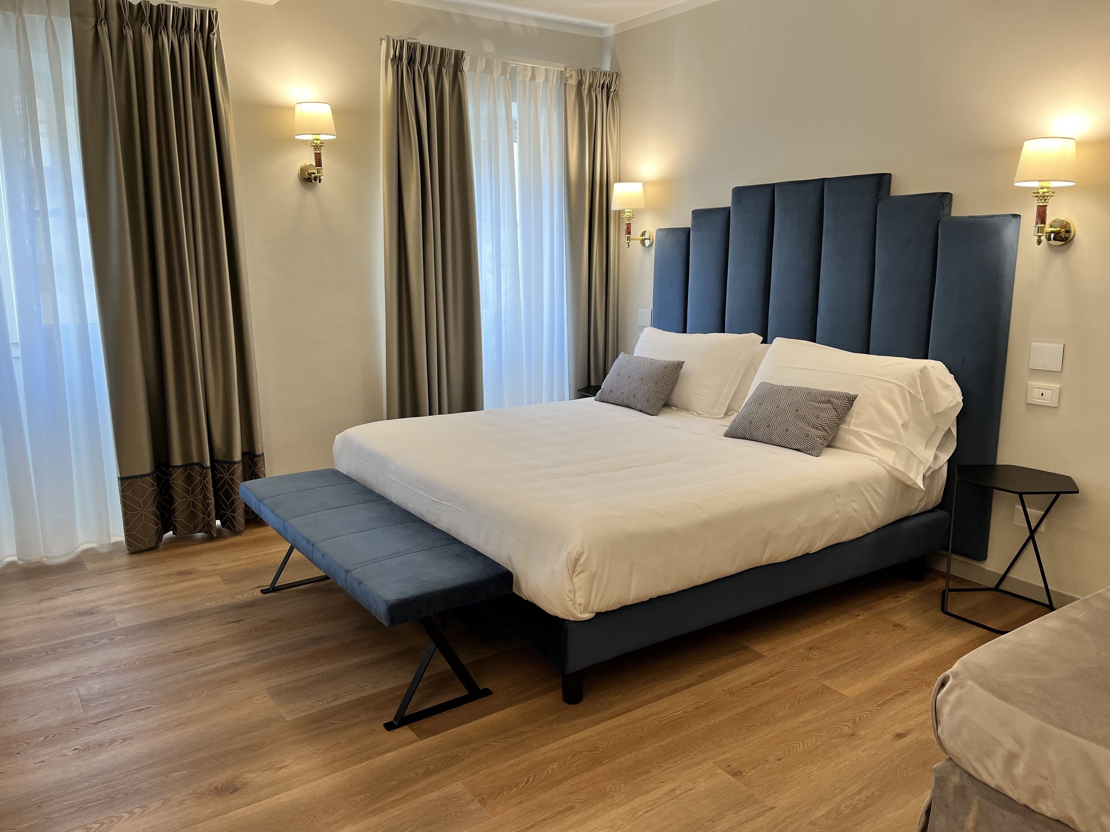 Ein modernes Schlafzimmer mit einem großen Bett, Nachttischen und Vorhängen.