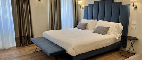 Ein modernes Schlafzimmer mit einem großen Bett, Nachttischen und Vorhängen.