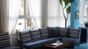 Een moderne woonkamer met een grijze bank, gekleurde kussens, een glazen salontafel en een kamerplant.