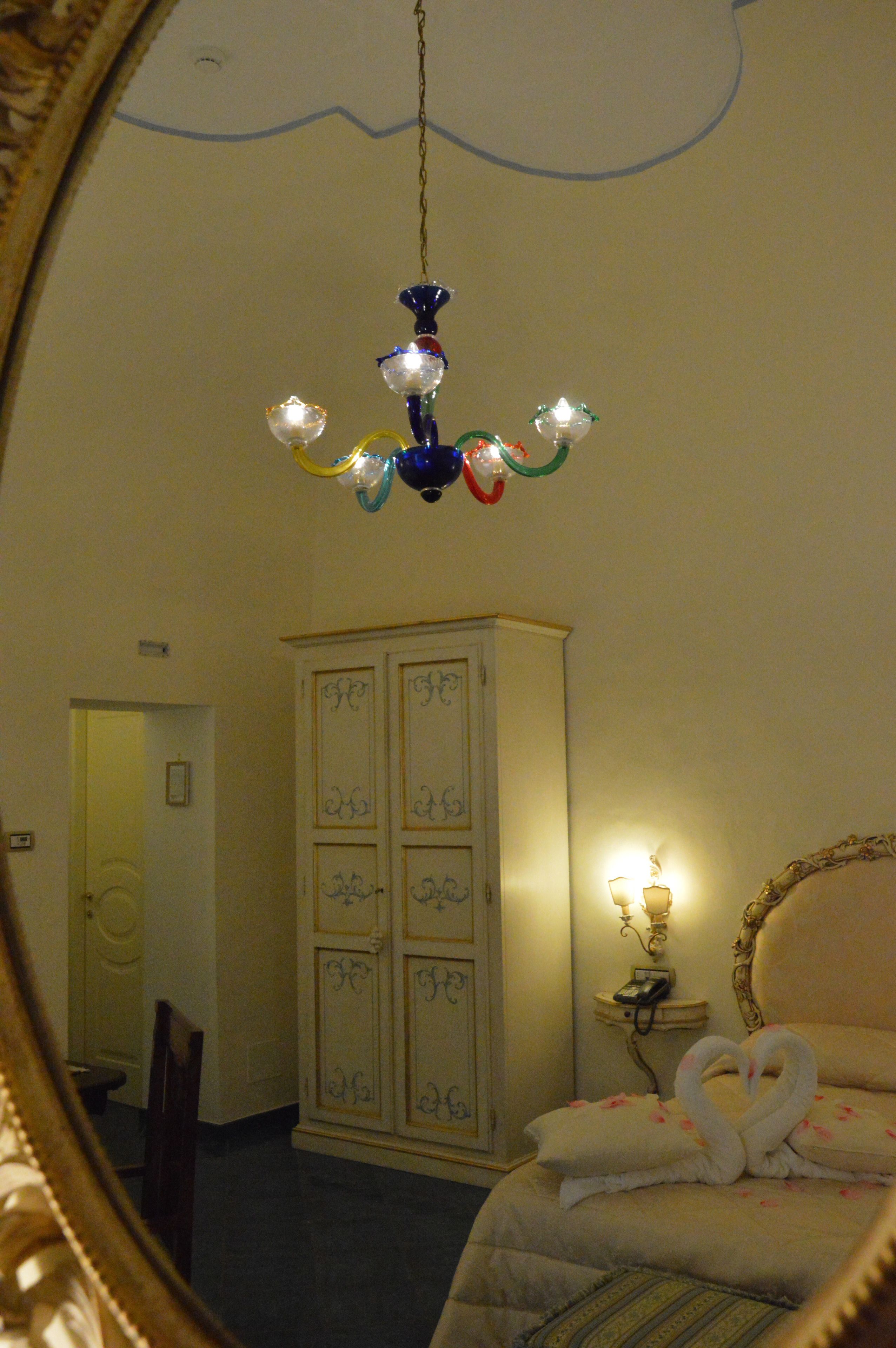 Un dormitorio con cama, armario, mesita de noche con lámpara y candelabro.