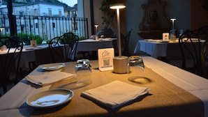 A dining table set with plates, glasses, and a QR code menu in a restaurant with a view of buildings and a balcony. - Hotel Santa Lucia (Minori)
