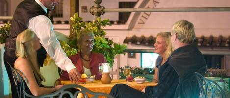 A dining table with a waiter serving food to guests.