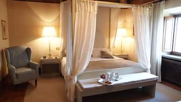 A four-poster bed with a canopy, bedside tables with lamps, a chair, and a breakfast tray on the bed.
