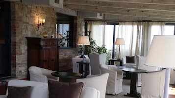 A spacious living room with a high ceiling, a fireplace, and a view of the outdoors.