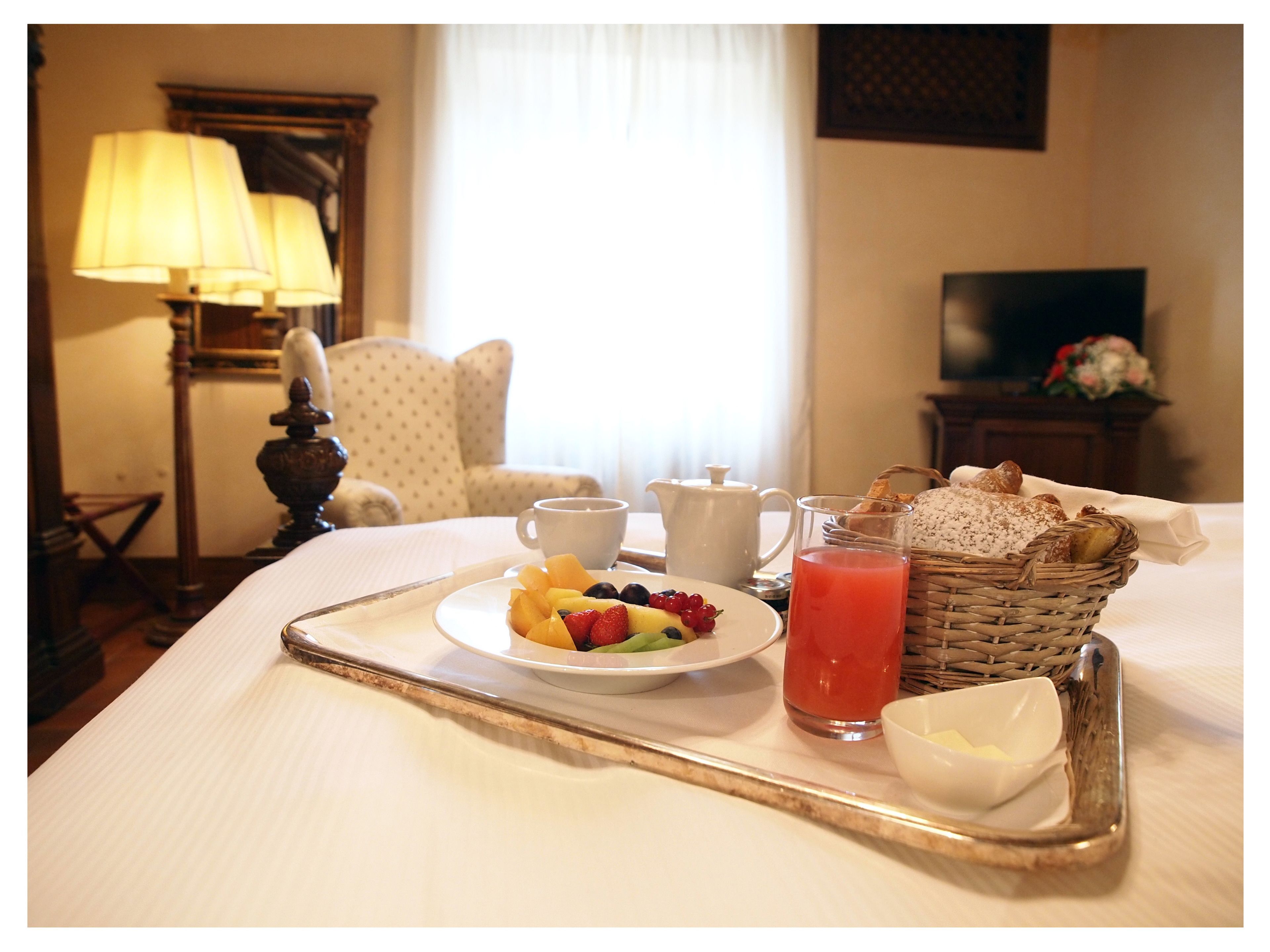 Un plateau de petit-déjeuner avec des fruits, du jus et du pain, posé sur une table dans une chambre d’hôtel.
