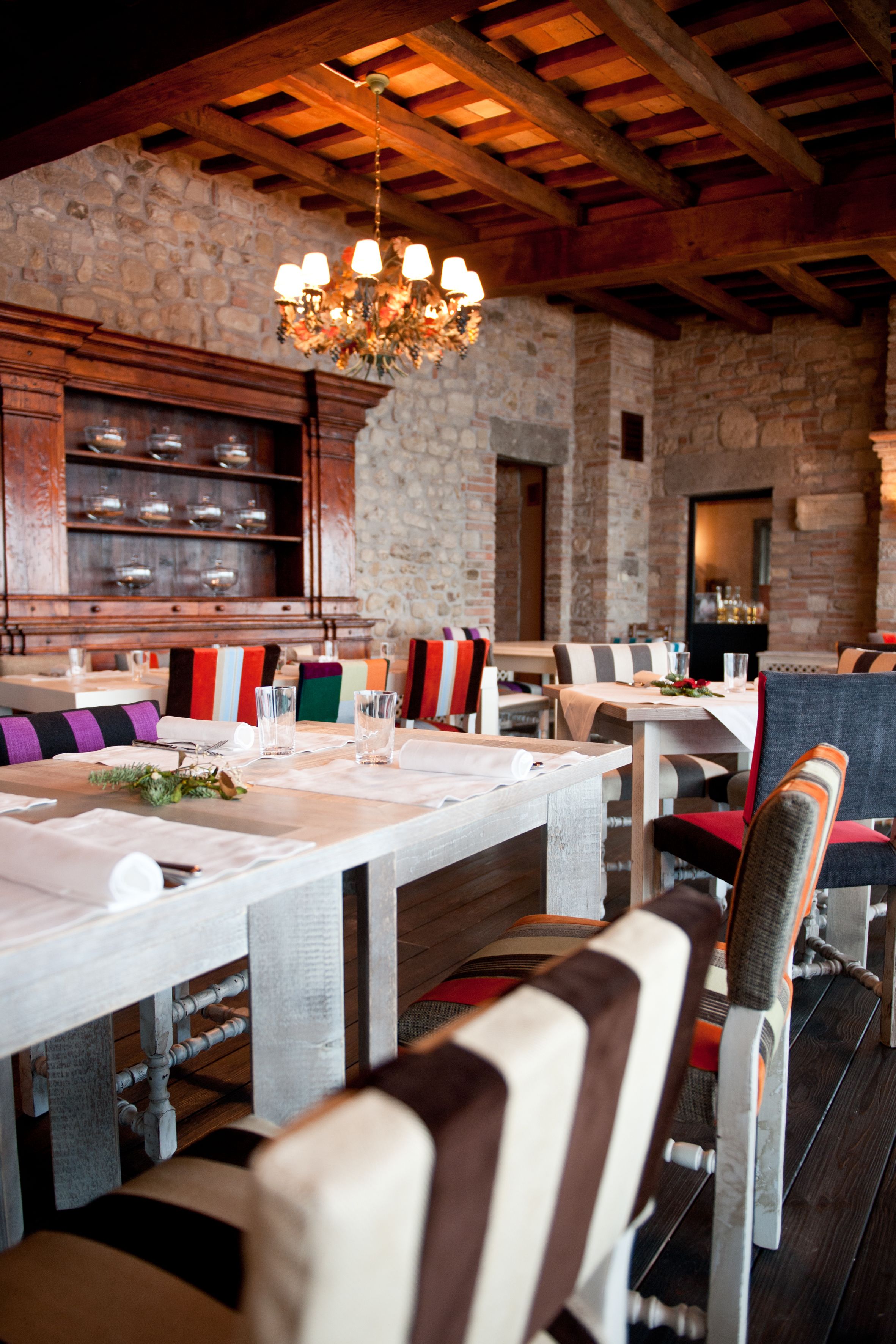 A restaurant with wooden tables, striped cushions, and a stone wall.