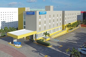 Um hotel City Express by Marriott com estacionamento, entrada coberta e fachada de edifício moderna.