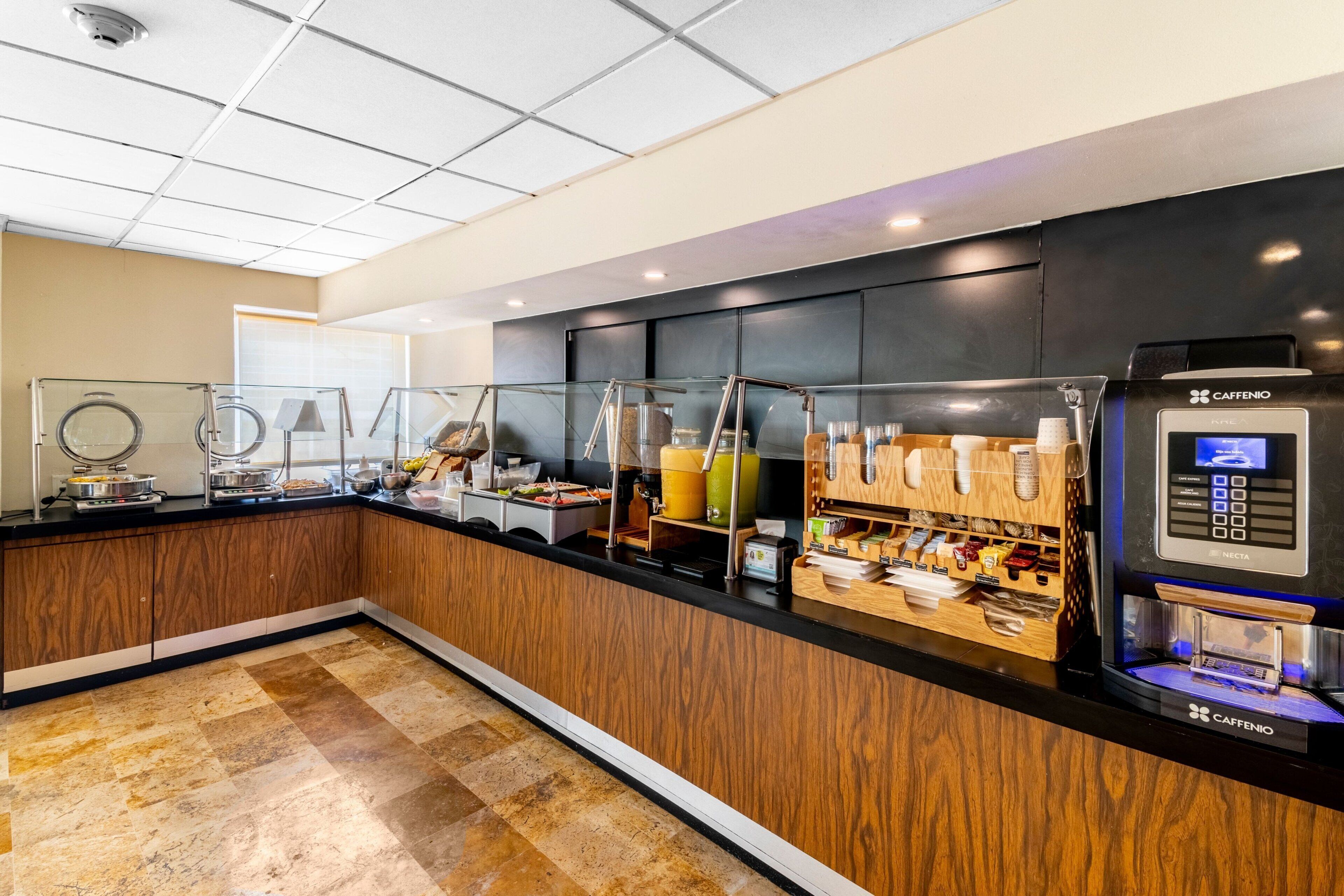A modern breakfast bar with a coffee machine, glass display cases, and a wooden counter.