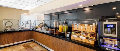 A modern breakfast bar with a coffee machine, glass display cases, and a wooden counter.