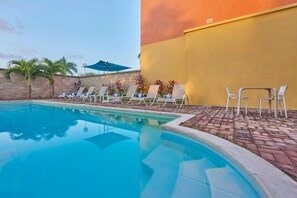 Una piscina al aire libre, sombrillas, sillones reclinables de piscina