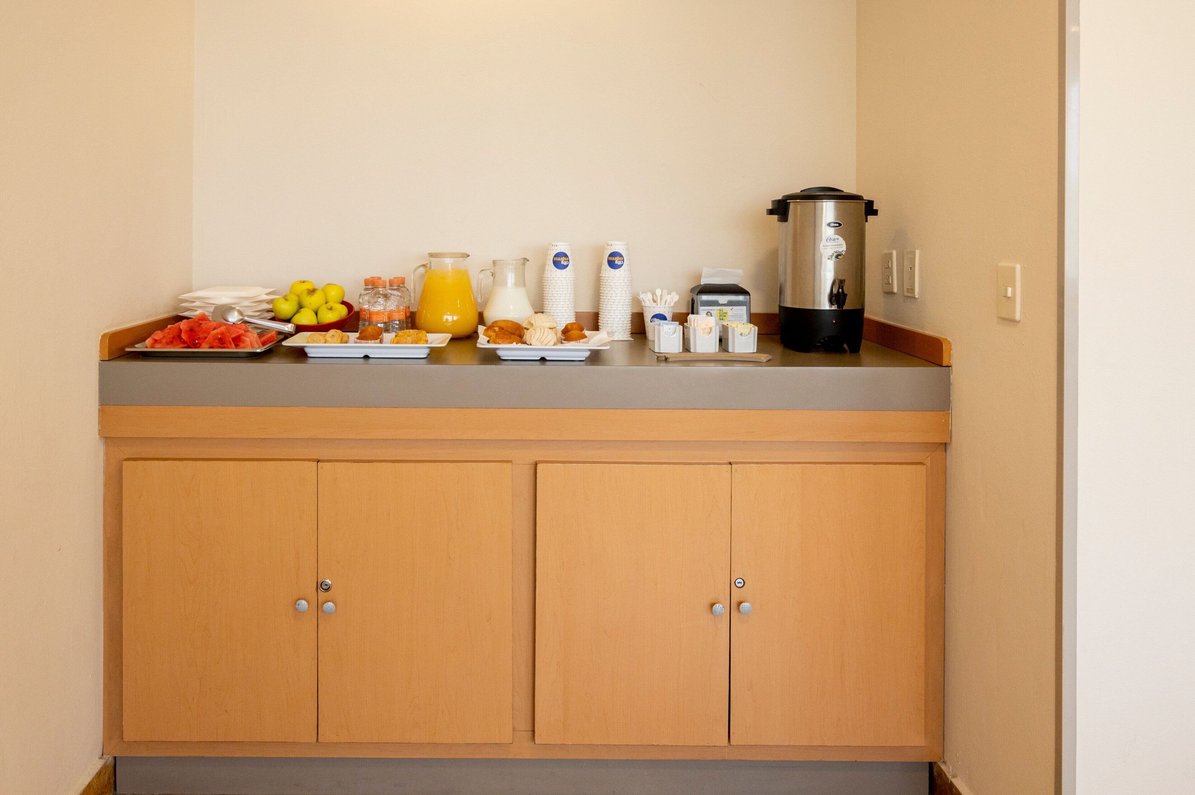 Un buffet de petit-déjeuner proposant une variété d'aliments et de boissons, notamment des fruits, des viennoiseries et une machine à café.