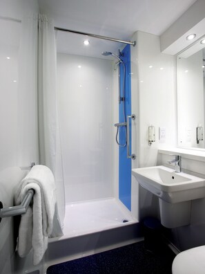 A modern bathroom with a shower, a sink, and a mirror. - Travelodge Manchester Sportcity (Manchester)