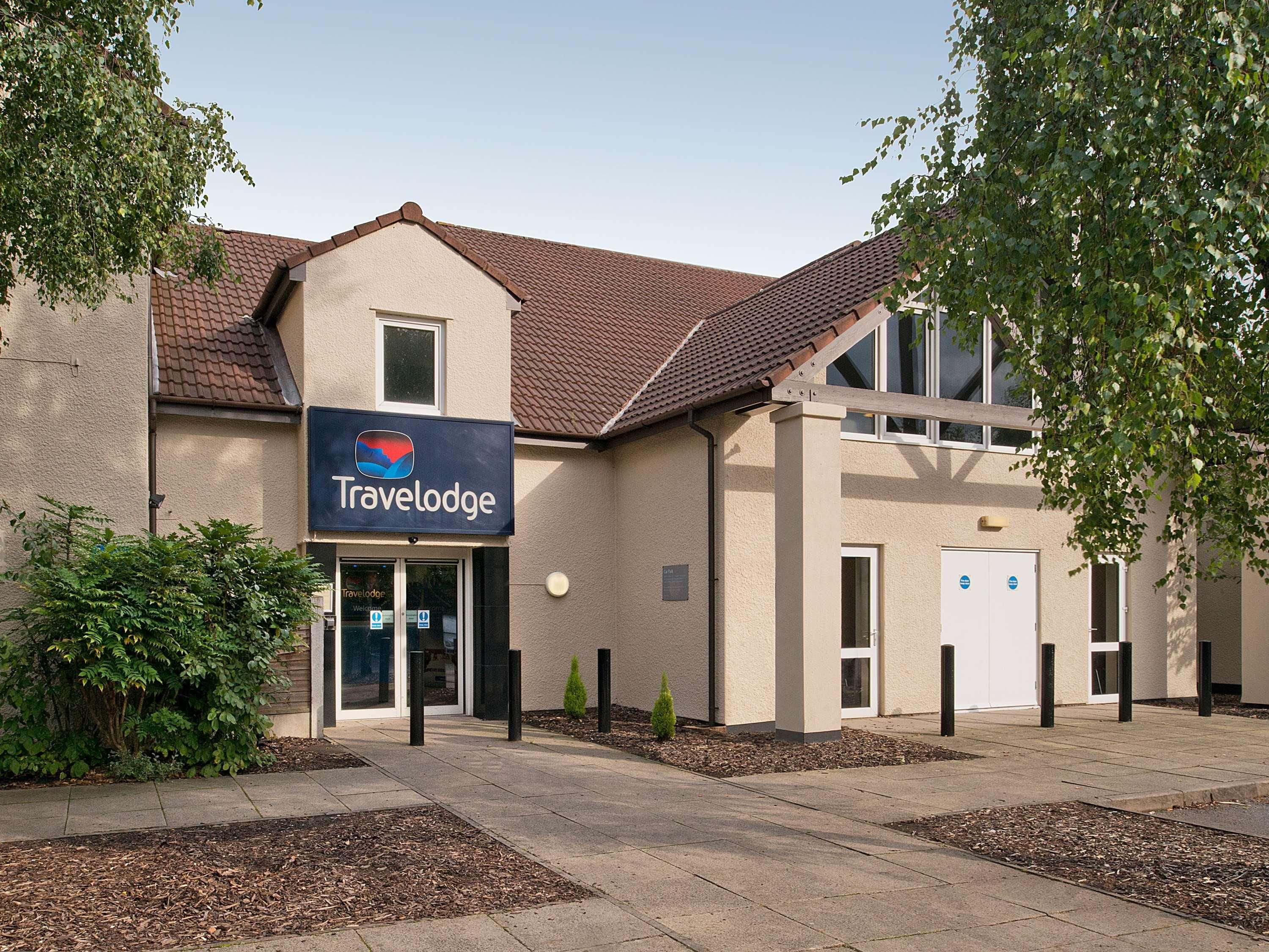 A Travelodge hotel with a modern facade, a tiled roof, and a landscaped entrance area.