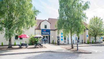 Ein Travelodge Hotel mit Schilder, Picknicktischen und einem Parkplatz.