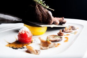 Un plato con un trozo de carne, un limón y algunas verduras.