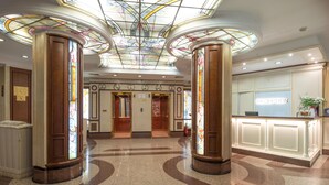 A lobby with a reception desk, stained glass columns, and a ceiling with skylights. - Hotel Downtown (Sofia)