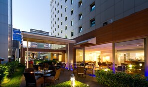 A hotel courtyard with outdoor seating, a glass-enclosed restaurant, and a modern building in the background. - Occidental Istanbul City (Istanbul)