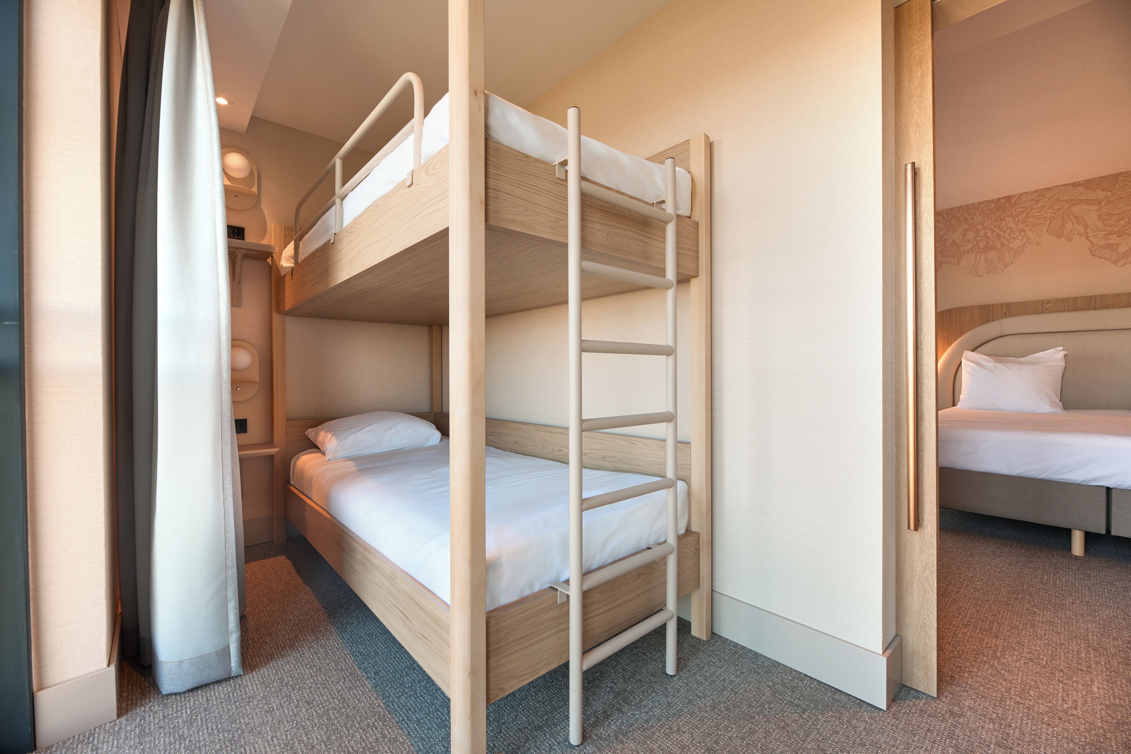 A bunk bed with a ladder, a single bed, and a carpeted floor.