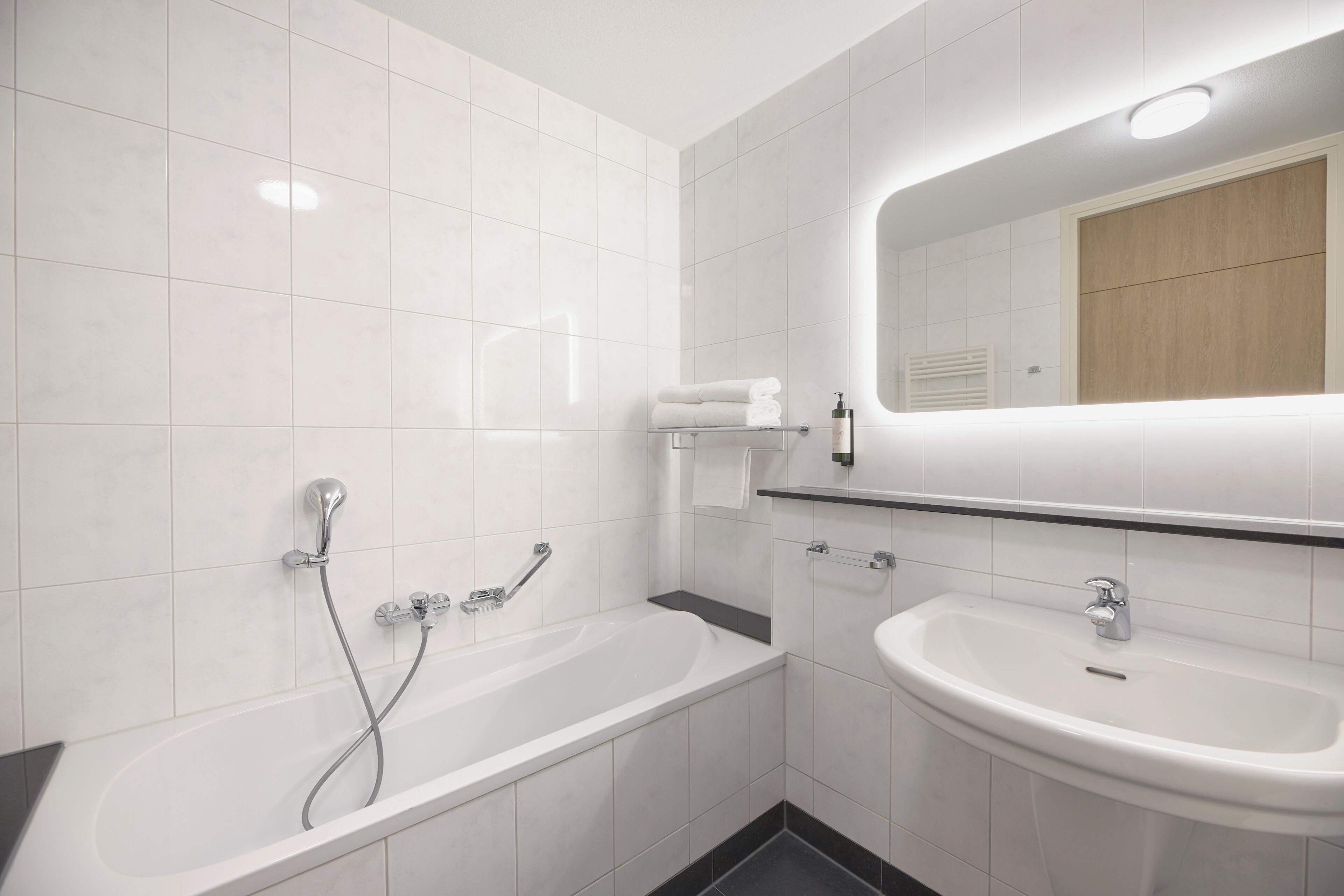 Un baño moderno con bañera, lavabo y espejo.