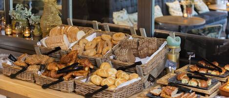 Una vitrina de panadería con panes y pasteles varios.