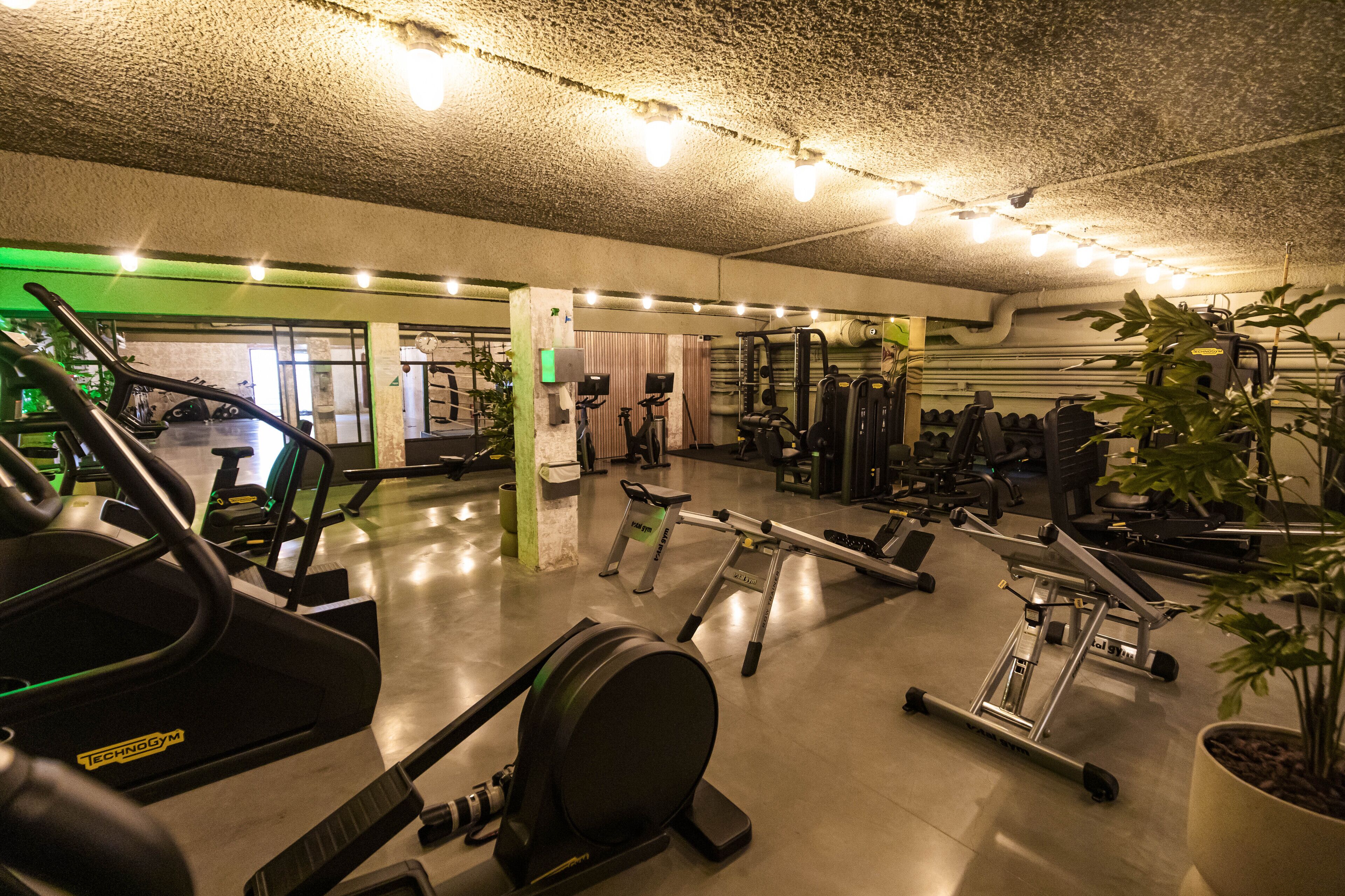 Un gimnasio con diverso equipo de ejercicio, incluyendo cintas de correr, elípticas y máquinas de pesas.
