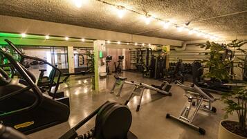 Un gimnasio con diverso equipo de ejercicio, incluyendo cintas de correr, elípticas y máquinas de pesas.