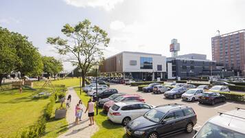 A parking lot with several cars, a playground, and a building with a sign that says "HOTEL".