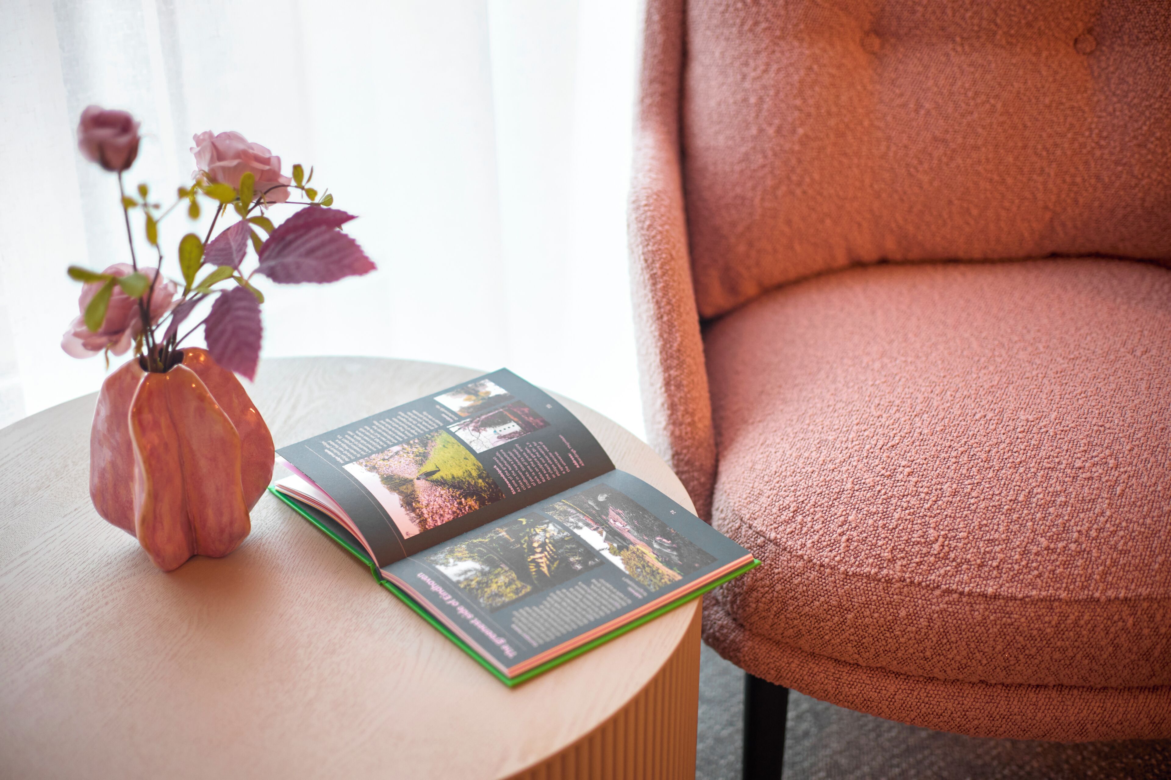 A book on a round table next to a chair.