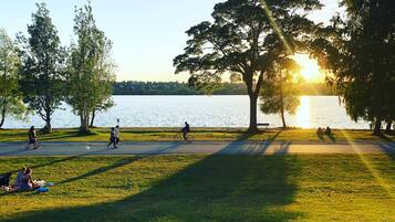 A park with a walking path, benches, and people engaging in various activities.