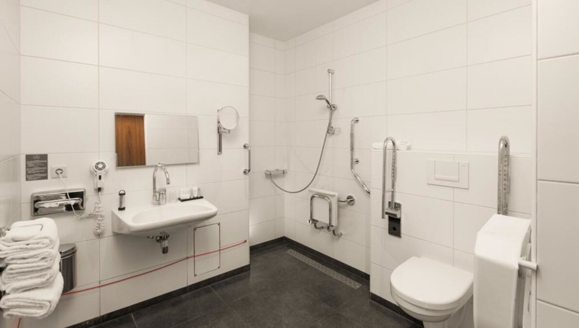 A modern bathroom with a sink, mirror, toilet, and shower.
