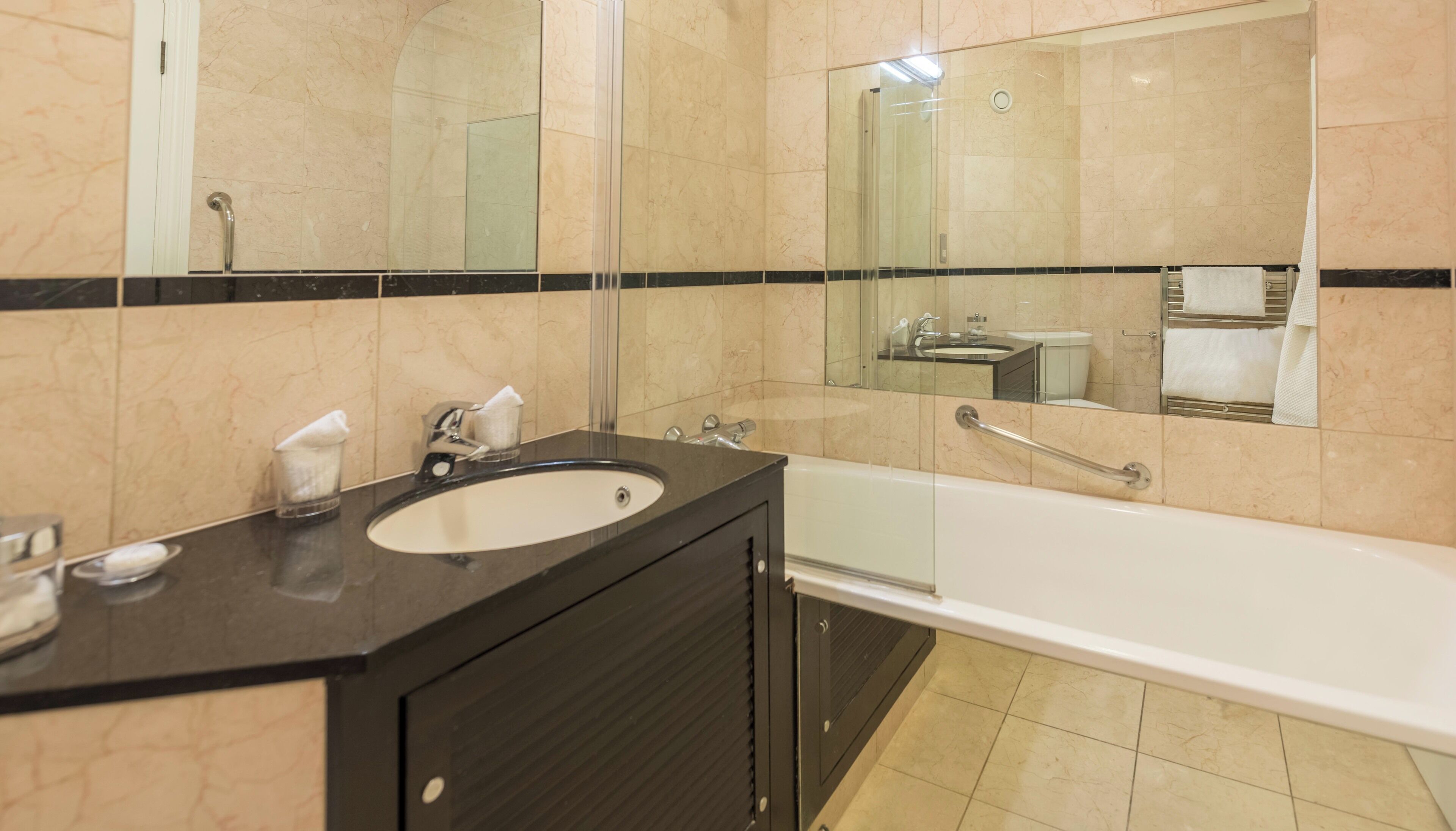 A modern bathroom with a large sink, mirror, and bathtub.