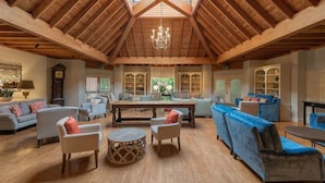 A spacious living area with wooden beams, a chandelier, and a large sofa set. - Careys Manor & Senspa (Brockenhurst)