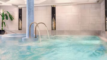 Un área de spa con una bañera de hidromasaje, dos pilares decorativos y una planta en maceta.