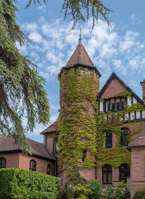 A brick tower with ivy, surrounded by a traditional building with multiple windows and a tiled roof. - Careys Manor & Senspa (Brockenhurst)