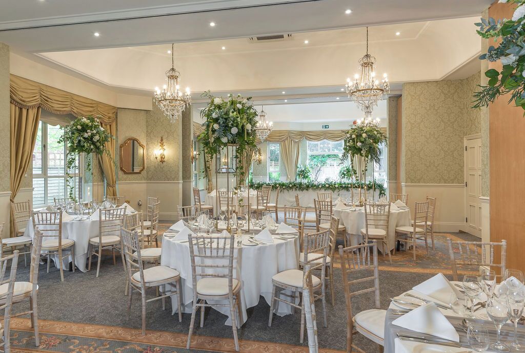 A banquet hall with round tables, white tablecloths, and floral centerpieces.