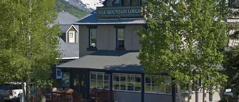 Una cabaña con un letrero que dice "ELK MOUNTAIN LODGE", un coche estacionado al frente y una montaña al fondo.