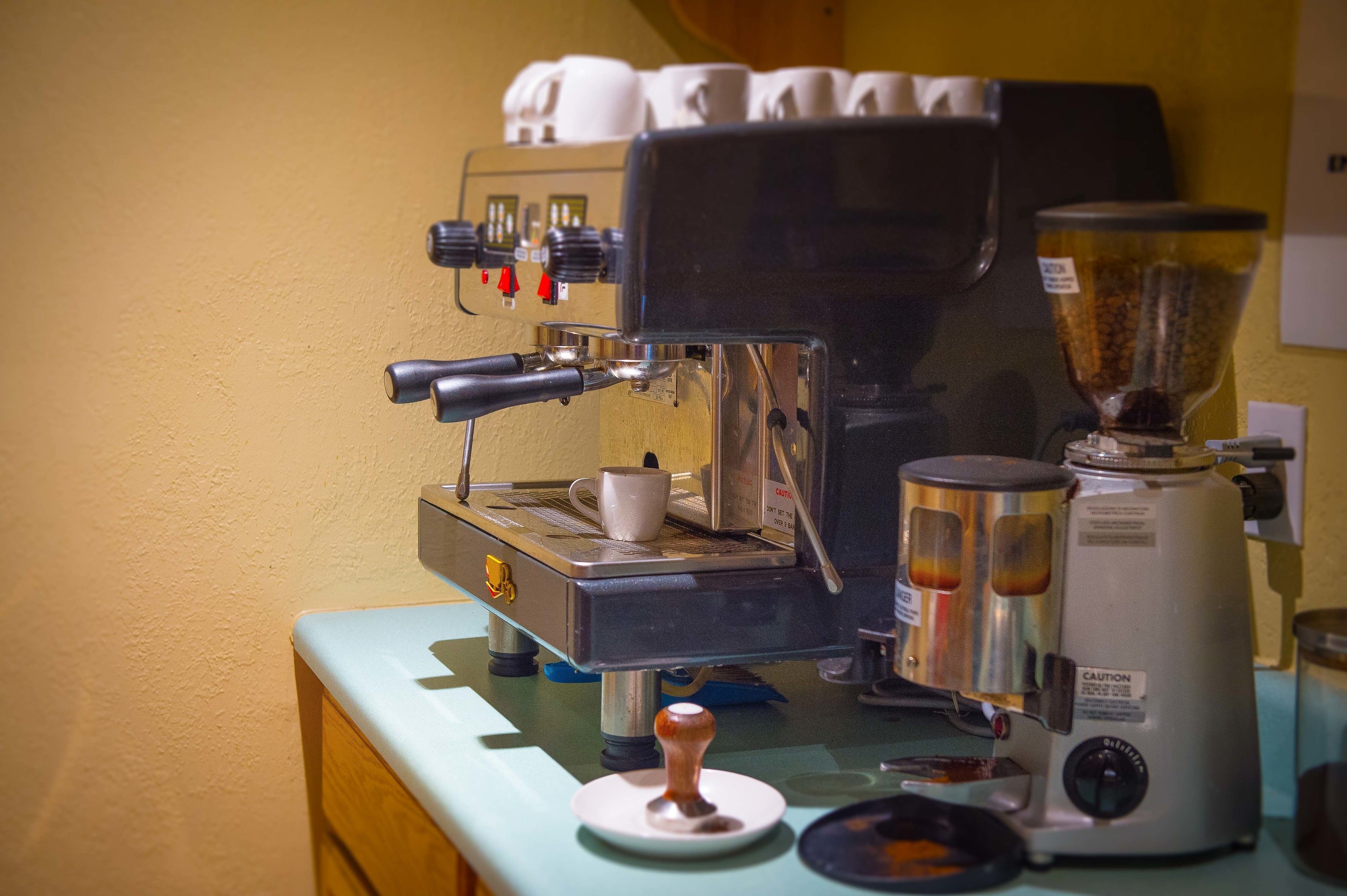 A coffee machine with a portafilter, a grinder, and a milk frother on a counter.